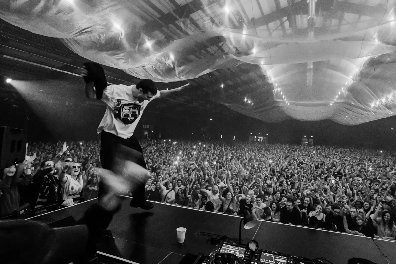 DJ jumping on stage in front of a cheering crowd